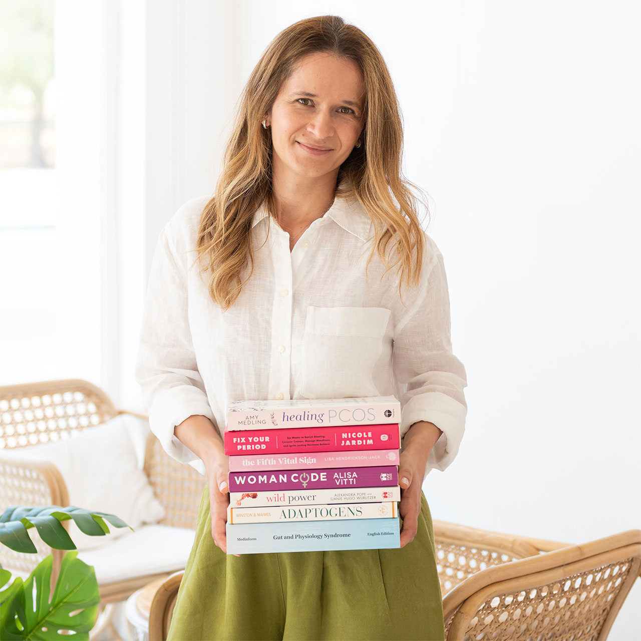 Iuliana holding a stack of books on women's health