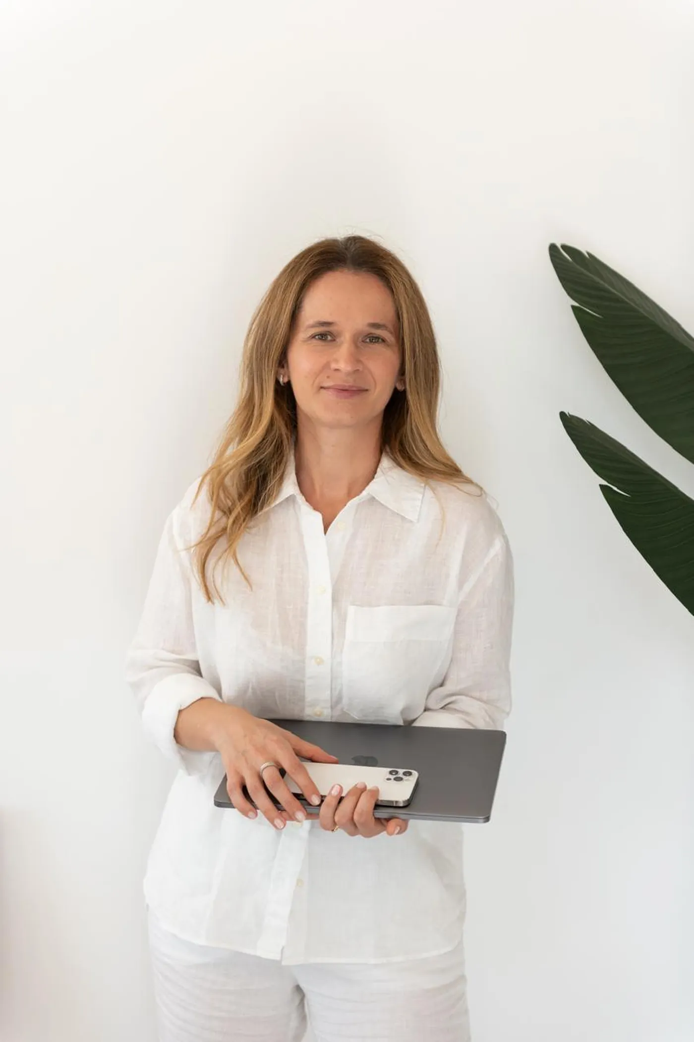 Iuliana standing with her laptop and phone in hand